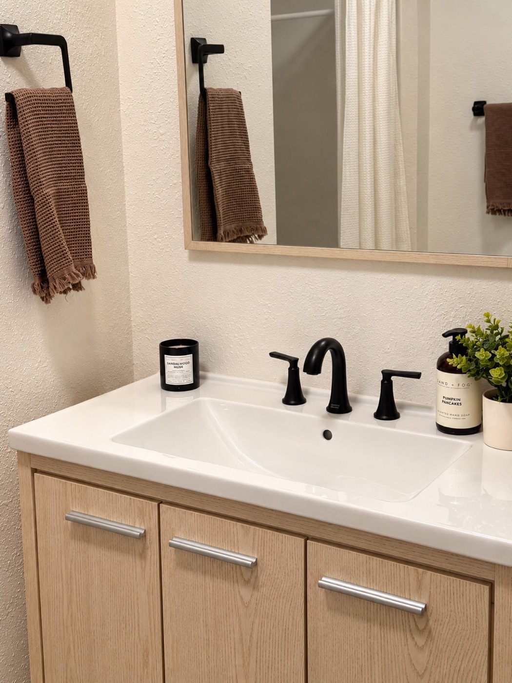 Light oak bathroom vanity with matte black faucet and hardware