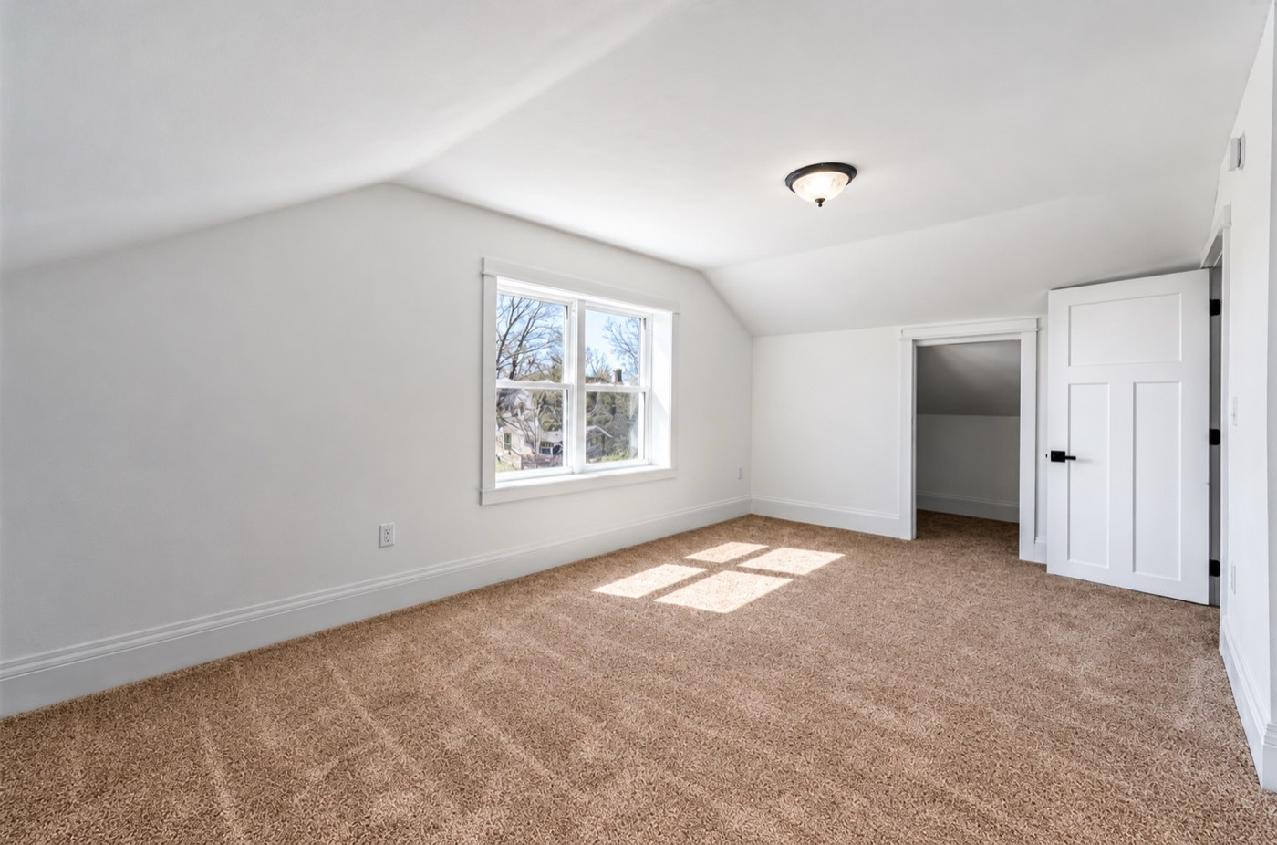 Upstairs bedroom with sloped ceiling, white trim and new carpet