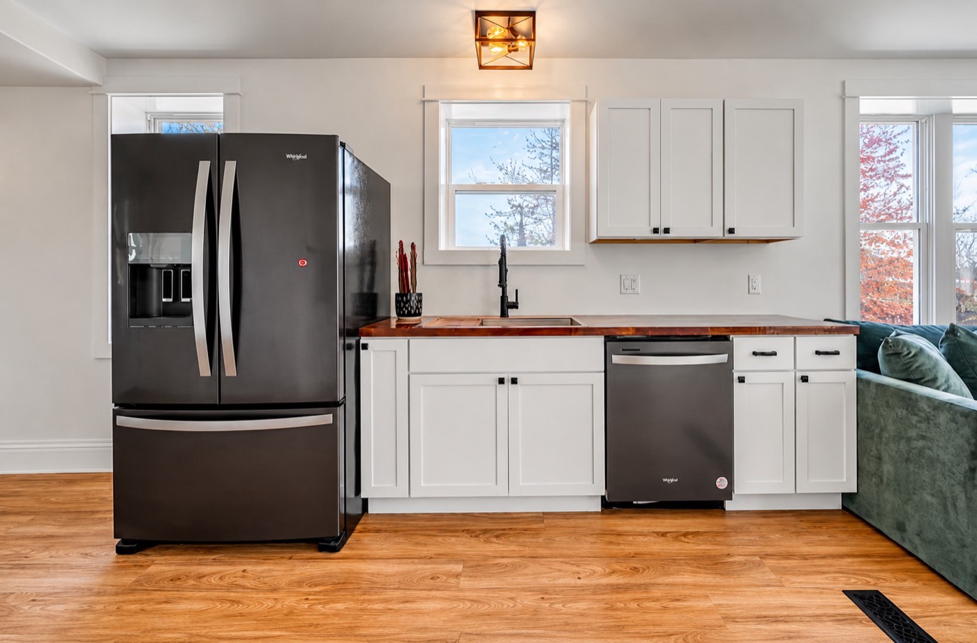 Kitchen wall with white shaker cabinets, wood countertop and matte black faucet