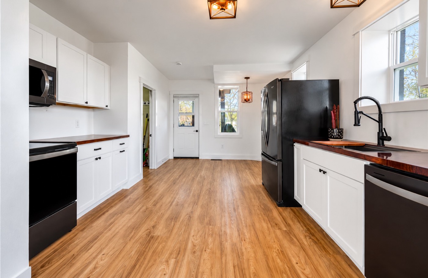 Remodeled kitchen with white shaker cabinets, wood countertops and black hardware