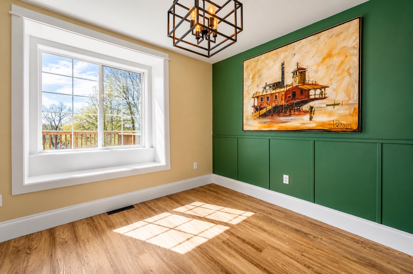 Room with green wainscot accent wall, window seat and plank flooring